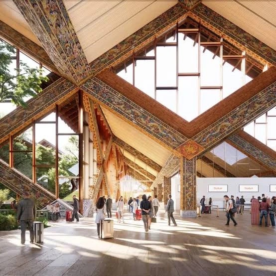 Rendering of a terminal hall under painted timber roof beams in traditional Bhutanese patterns, with travellers and check-in desks.